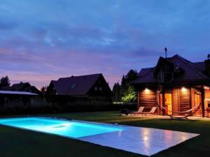 a swimming pool in front of a house at night at Holiday Home Drewniany z bala by Interhome in Dębki