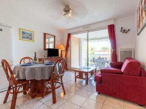 een woonkamer met een tafel en een rode bank bij Apartment Les Calanques du Parc-3 by Interhome in Saint-Aygulf