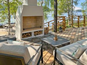 a patio with a fireplace with chairs and a table at Holiday Home Villa saimaan joutsenlahti by Interhome in Äitsaari