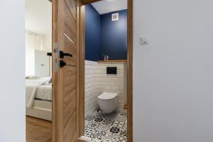 a bathroom with a toilet and a blue wall at Salt Island Apartment Sea and Harbor View by Renters in Kołobrzeg