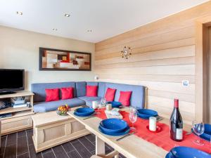 a living room with a table and a blue couch at Apartment Le Bec Rouge - Le Lac-9 by Interhome in Tignes