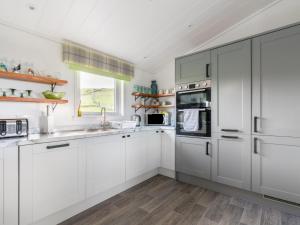 een witte keuken met witte kasten en een raam bij Chalet Loch Leven Lodge 16- Robin's Nest by Interhome in Kinross