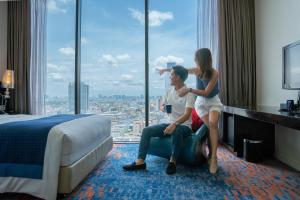 mężczyzna i kobieta siedzący w pokoju hotelowym z oknem w obiekcie Holiday Inn Express Bangkok Siam, an IHG Hotel w mieście Bangkok