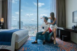 un uomo e una donna seduti in una stanza d'albergo con una finestra di Holiday Inn Express Bangkok Siam, an IHG Hotel a Bangkok