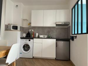 une cuisine avec des armoires blanches et une laveuse et une sécheuse dans l'établissement L'avalasse - Petit appartement centre de Rouen - 121, à Rouen