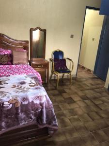 ein Schlafzimmer mit einem Bett, einer Kommode und einem Stuhl in der Unterkunft Bel Appartement meublé à Bafoussam in Bafoussam