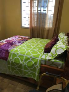 - un lit vert et blanc dans une chambre avec fenêtre dans l'établissement Bel Appartement meublé à Bafoussam, à Bafoussam
