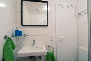a white bathroom with a sink and a mirror at Ferienwohnung Ausblick in Norddeich +13 photos