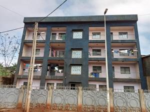 ein Gebäude mit einem Zaun davor in der Unterkunft Bel Appartement meublé à Bafoussam in Bafoussam
