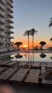 basen z leżakami, palmami i zachodem słońca w obiekcie Hotel Ocean House Costa del Sol, Affiliated by Meliá w mieście Torremolinos