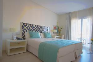 - une chambre blanche avec un grand lit et une fenêtre dans l'établissement Al Mandari Hôtel Tétouan, à Tetouan