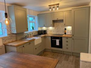 a kitchen with white cabinets and a wooden table at Buttercup Cottage, located in the gateway to Eden! in Saint Blazey