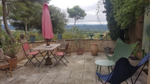 eine Terrasse mit Stühlen, einem Tisch und einem Sonnenschirm in der Unterkunft La Maison de Charlie in Vaugines