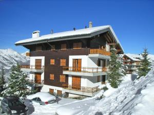 a building in the snow with a car parked in front at Apartment Les Crêtes 1-4 by Interhome in Veysonnaz