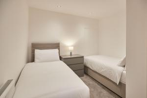 ein Schlafzimmer mit 2 Betten und einem Nachttisch mit einer Lampe in der Unterkunft Host & Stay - High Street Apartments in Caernarfon