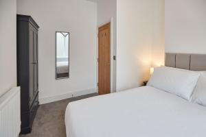 a bedroom with a white bed and a mirror at Host & Stay - High Street Apartments in Caernarfon