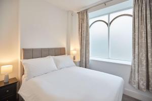 een slaapkamer met een wit bed en een raam bij Host & Stay - High Street Apartments in Caernarfon