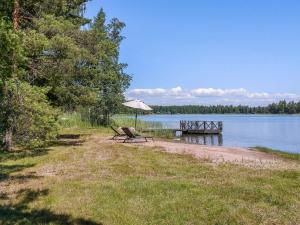 a picnic table and an umbrella on the shore of a lake at Holiday Home Villa blombacka by Interhome in Isnäs