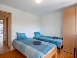 2 Betten in einem Zimmer mit blauer Bettwäsche in der Unterkunft Apartment Tasman S16-R by Interhome in Bouveret