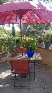 una mesa con una silla roja y una sombrilla rosa en La Maison de Charlie, en Vaugines