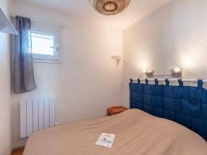 um quarto com uma cama com uma cabeceira azul e uma janela em Apartment Ortal Océan-9 by Interhome em Lacanau-Océan
