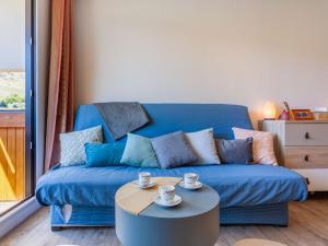 a blue couch in a living room with a coffee table at Apartment Soyouz Vanguard-95 by Interhome in Le Corbier