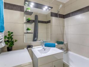 a bathroom with a sink and a tub and a mirror at Apartment Soyouz Vanguard-95 by Interhome in Le Corbier