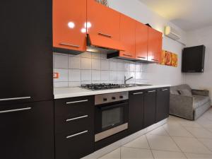 a kitchen with orange cabinets and a stove top oven at Apartment Rosapanna-2 by Interhome in Rosapineta