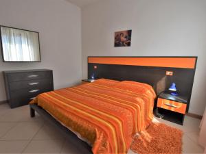 a bedroom with a large bed with an orange blanket at Apartment Rosapanna-2 by Interhome in Rosapineta