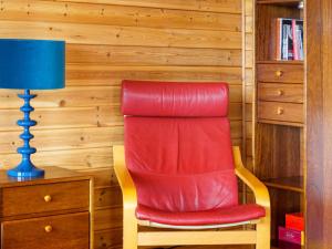 a red chair sitting next to a desk with a blue lamp at Chalet Lodge 9 by Interhome in Kinross