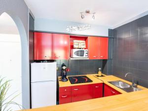 a kitchen with red cabinets and a white refrigerator at Apartment Puigmal by Interhome in Empuriabrava
