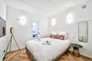 een witte slaapkamer met een groot bed en een spiegel bij Splendide appartement pour 6 proche Montmartre in Parijs
