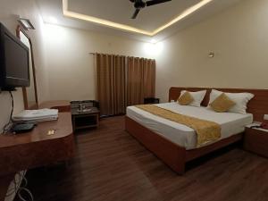 um quarto de hotel com uma cama e uma televisão em Hotel Padmini International- Sigra em Kakarmatha
