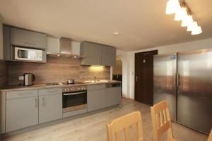 a kitchen with gray cabinets and a stainless steel refrigerator at Chalet Edelweiss in Zell am See