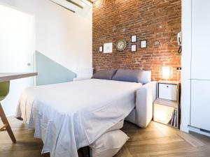 a white bed in a room with a brick wall at Emma's home Monza in Monza