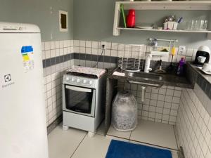 a small kitchen with a stove and a sink at Ed Bertholi - Frente ao mar com garagem in Serra
