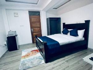 um quarto com uma cama com lençóis azuis e piso em madeira em Abby Studio Apartment with Swimming Pool em Nanyuki