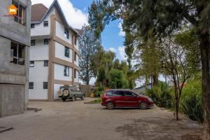 a red car parked in a parking lot next to a building at Abby Studio Apartment with Swimming Pool in Nanyuki