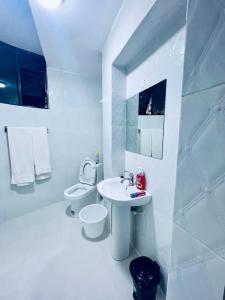 a white bathroom with a sink and a toilet at Abby Studio Apartment with Swimming Pool in Nanyuki