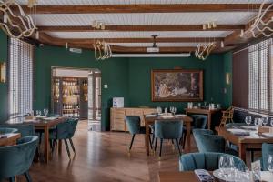 a restaurant with wooden tables and chairs and green walls at Дом у озера in Shchūchīnsk