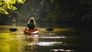a woman is sitting on a kayak in the water at Luna et Sol - Haus am See großes Apartment in Seehausen