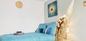 Zimmer mit einem Bett mit blauer Bettwäsche und einer Uhr in der Unterkunft The Sky - Dormez sur un petit nuage in Dreux