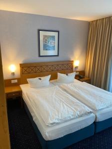 a bedroom with a large bed with white sheets and pillows at Strandhotel Seestern in Baabe