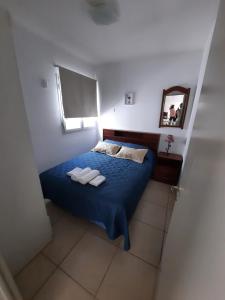 a bedroom with a bed with blue sheets and a mirror at Caseros Centro in San Juan