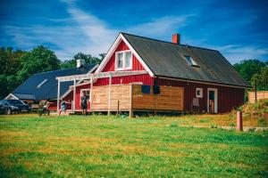a red barn with a woman and a child standing in front of it at Waldhouse in Olofström