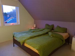 ein Schlafzimmer mit einem Bett mit grüner Bettdecke und einem Fenster in der Unterkunft Waldhouse in Olofström