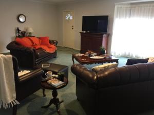 sala de estar con muebles de cuero y TV en Bird Abode, en Maryborough