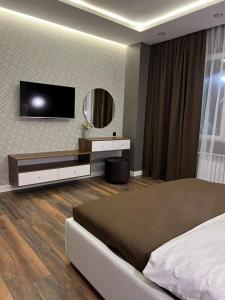 a bedroom with a bed and a tv on a wall at Dream Hotel in Almaty