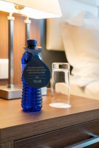 una botella azul en una mesa junto a un vaso en Costé Hotel, en Tiflis