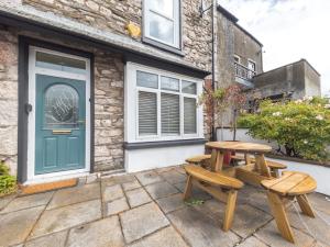 two picnic tables in front of a building with a door at Pass the Keys Cosy Cottage Nestled in the Center of Ulverston in Ulverston